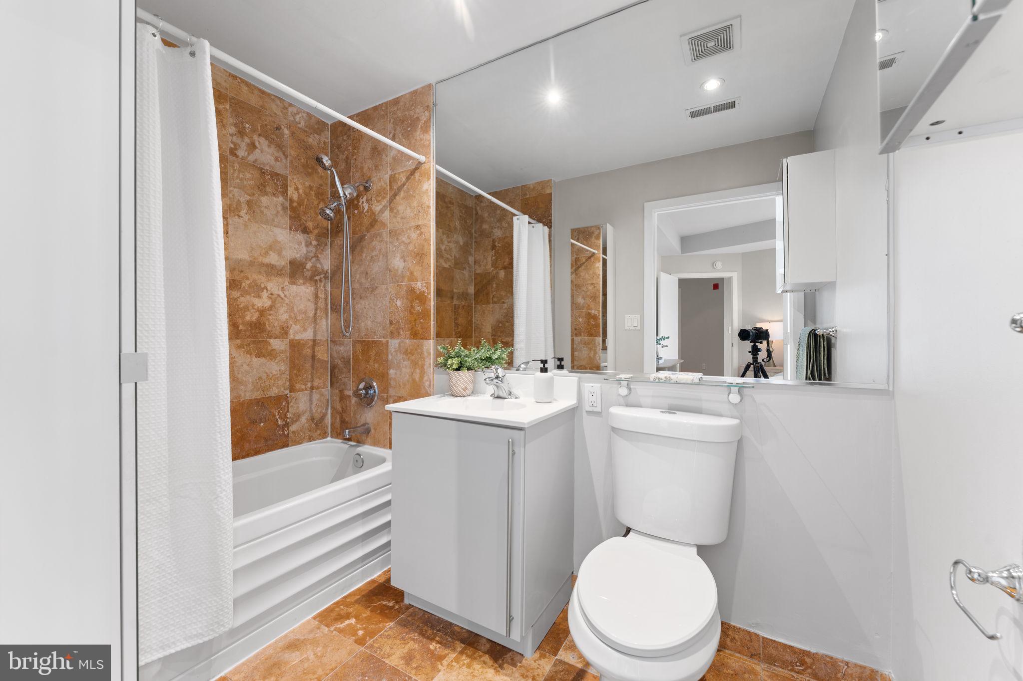 1300 13th Street Northwest, Unit 603 Washington, DC 20005 - Photo 14 of 26 a bathroom with a sink a toilet a mirror and bathtub