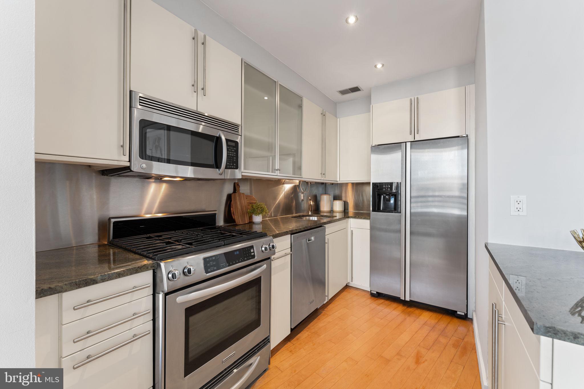 1300 13th Street Northwest, Unit 603 Washington, DC 20005 - Photo 8 of 26 a kitchen with stainless steel appliances granite countertop a stove a refrigerator and a microwave