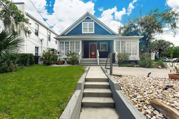 a front view of a house with a yard and potted plants
