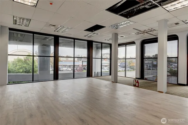an empty room with large windows and ceiling fan