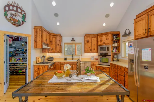 a view of a kitchen with stainless steel appliances granite countertop a refrigerator and a stove top oven