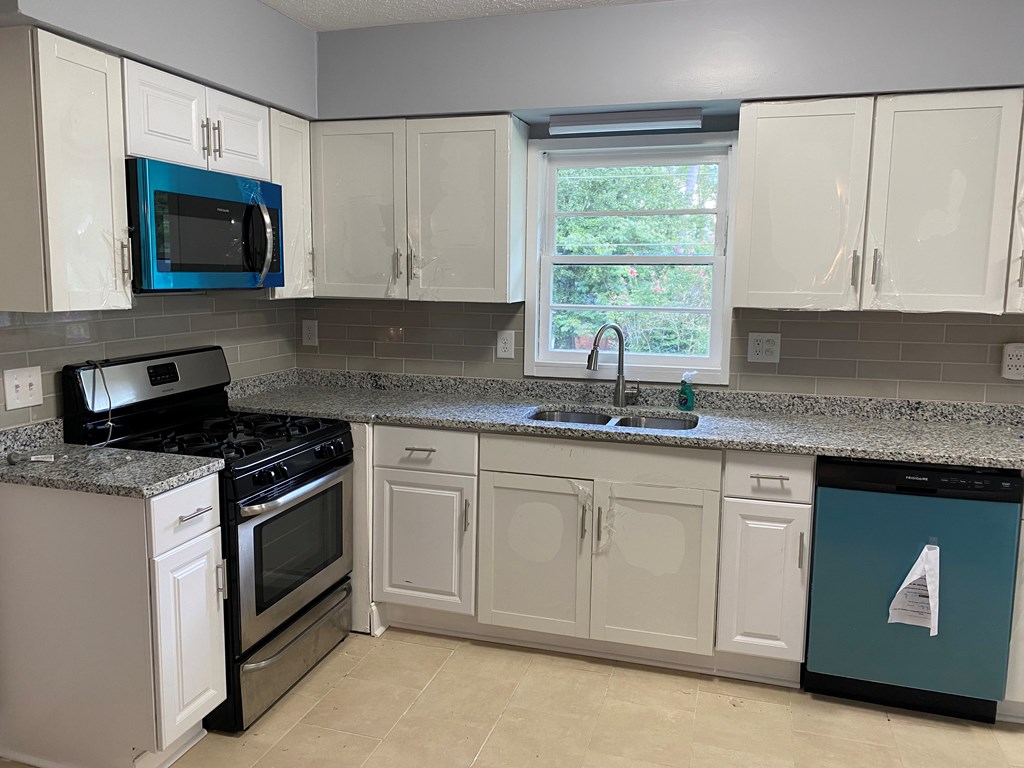1061 Dunbar Avenue Columbus, GA 31906 - Photo 4 of 11 a kitchen with granite countertop white cabinets appliances a window and a sink