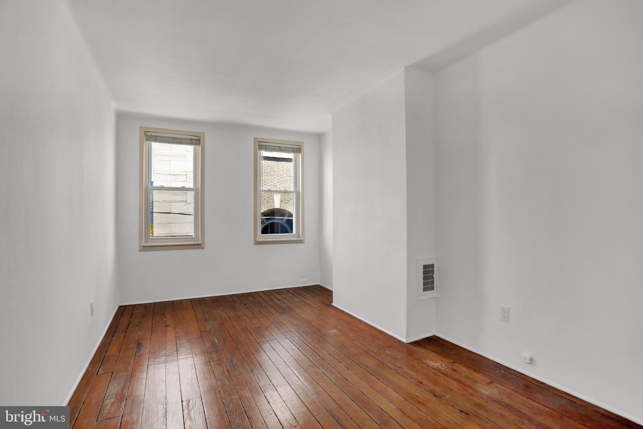 1306 Rutter Street Baltimore, MD 21217 - Photo 19 of 27 an empty room with wooden floor and windows
