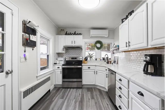 a kitchen with stainless steel appliances a stove a sink and white cabinets