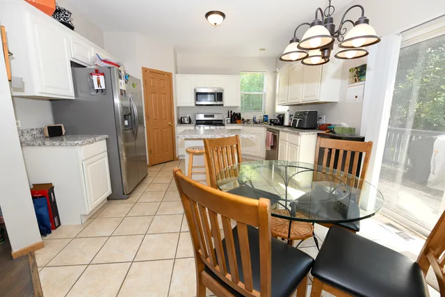 a kitchen with stainless steel appliances granite countertop a stove a refrigerator a kitchen island a dining table and chairs