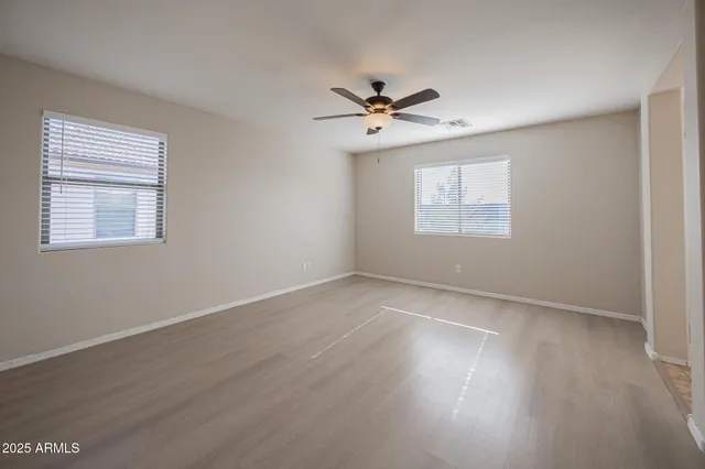 a view of empty room with wooden floor and fan