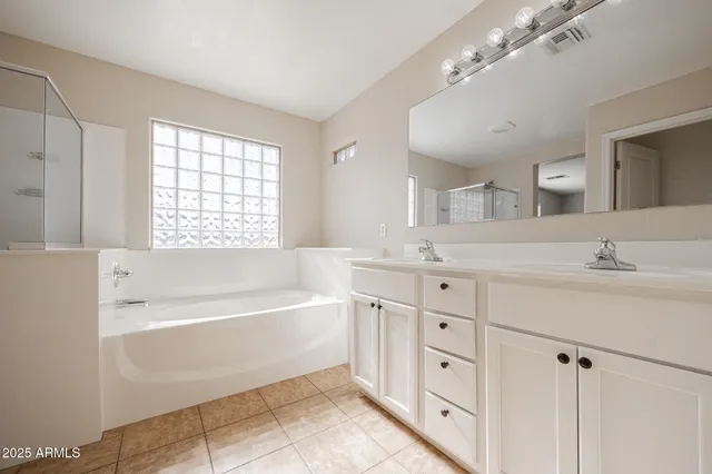 a spacious bathroom with a double vanity sink large mirror and a bathtub