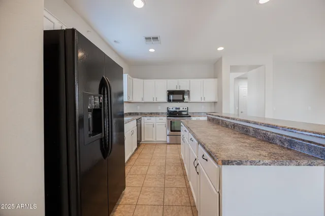 a kitchen with stainless steel appliances granite countertop a refrigerator a stove and a sink