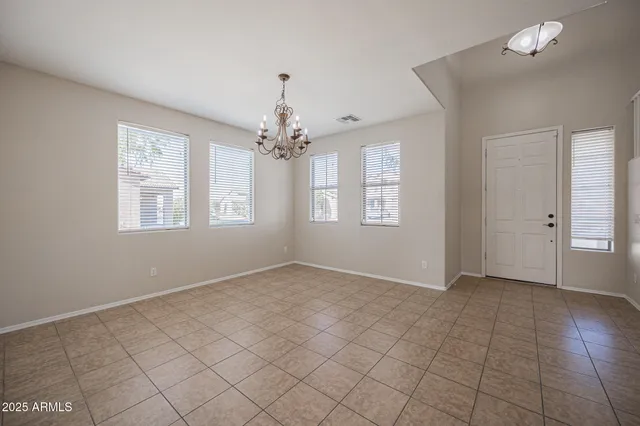 an empty room with windows and chandelier fan