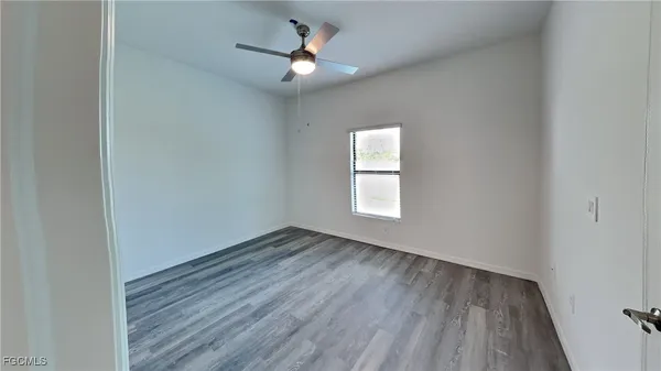 an empty room with a window and a fan
