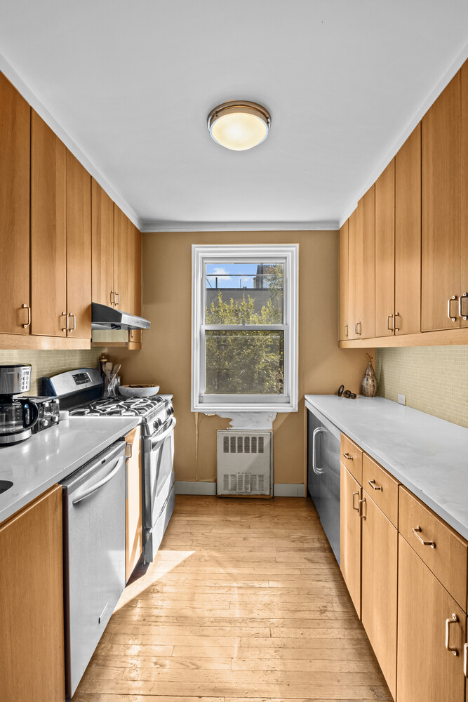 2465 Palisade Avenue, Unit 7H Bronx, NY 10463 - Photo 5 of 15 a kitchen with stainless steel appliances granite countertop a stove a sink dishwasher and a microwave oven with white cabinets