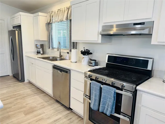 a kitchen with stainless steel appliances granite countertop a sink a stove a refrigerator and island with wooden floor