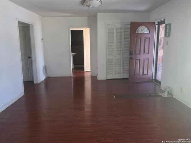 an empty room with wooden floor closet and windows