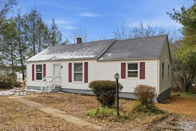 a view of a house with a yard chairs and wooden fence