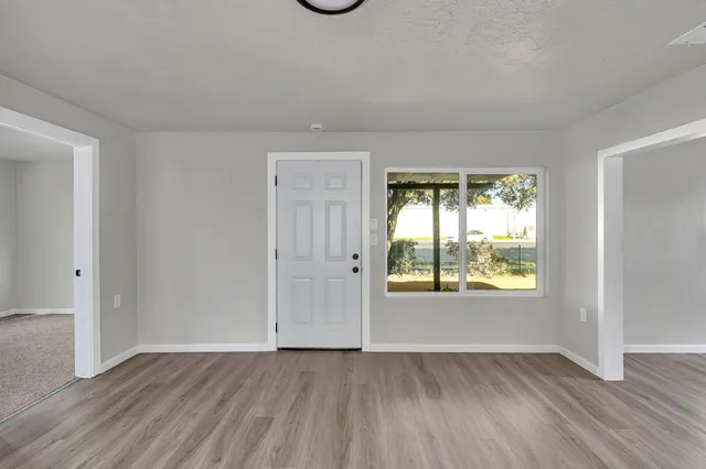 a view of an empty room with wooden floor and a window