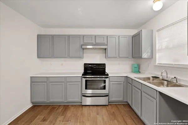 a kitchen with stainless steel appliances a stove and white cabinets