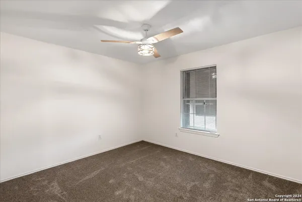an empty room with a window and ceiling fan