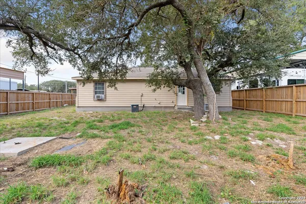 a backyard of a house with large trees and brick walls