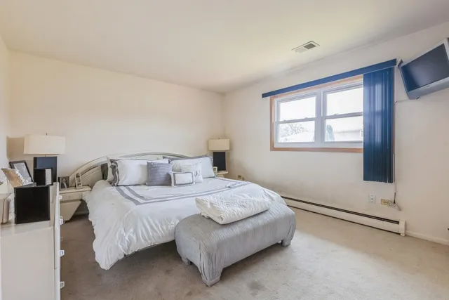 a bedroom with a bed lamp and a large window