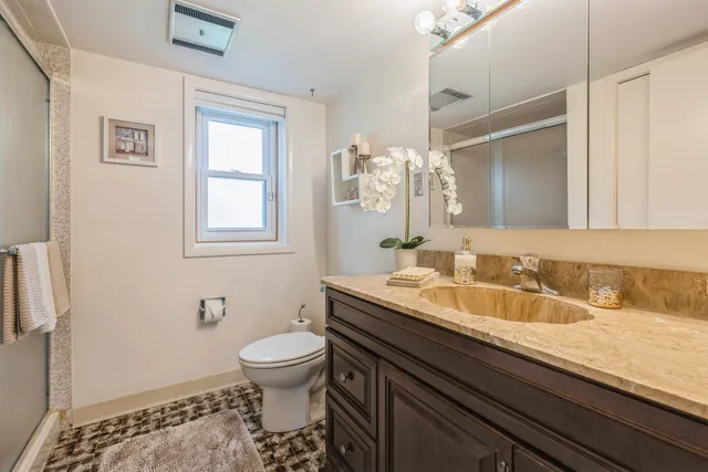 a bathroom with a granite countertop sink a toilet and a mirror