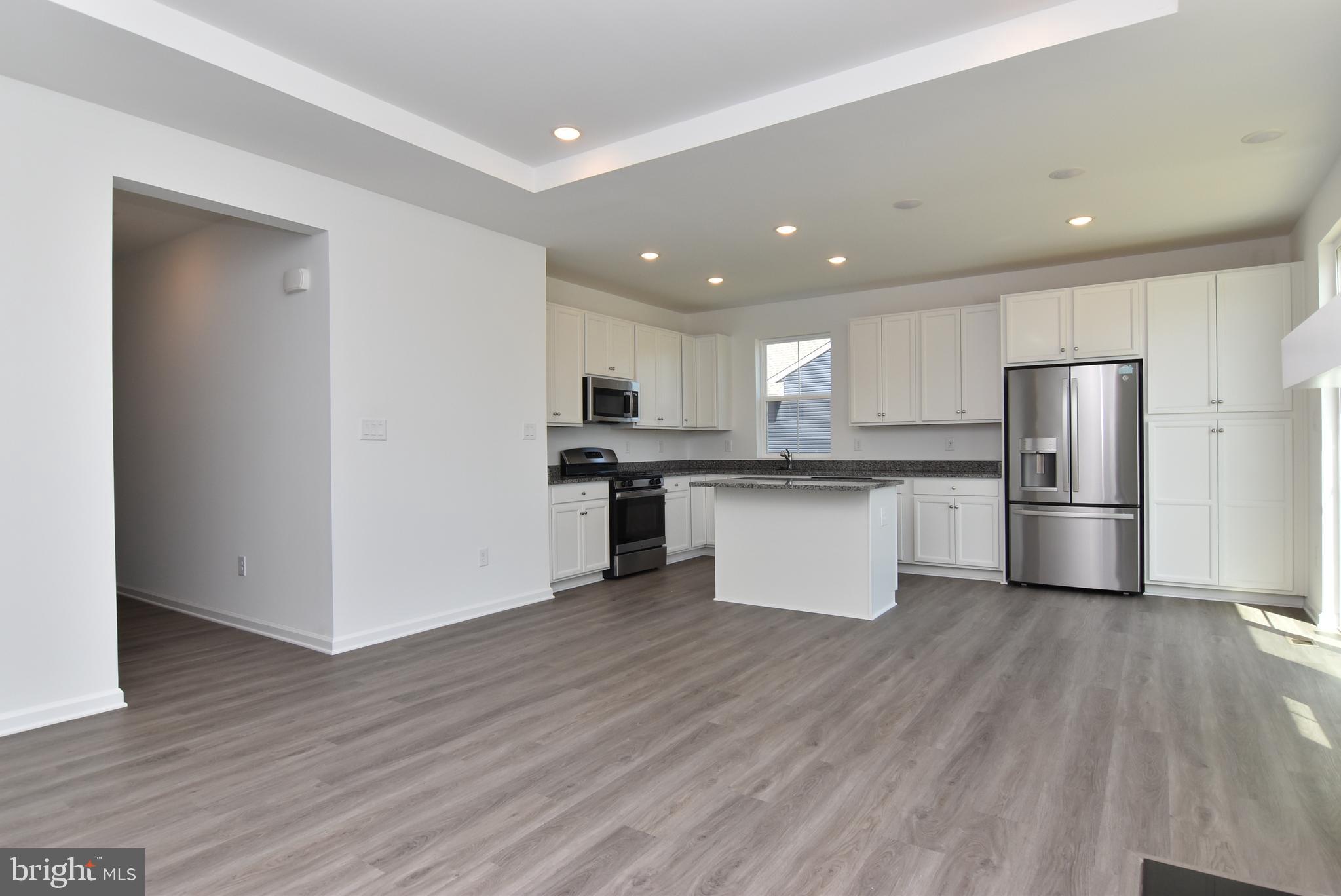 36366 Gate Drive Georgetown, DE 19947 - Photo 4 of 23 a kitchen with stainless steel appliances granite countertop a refrigerator a stove top oven and white cabinets