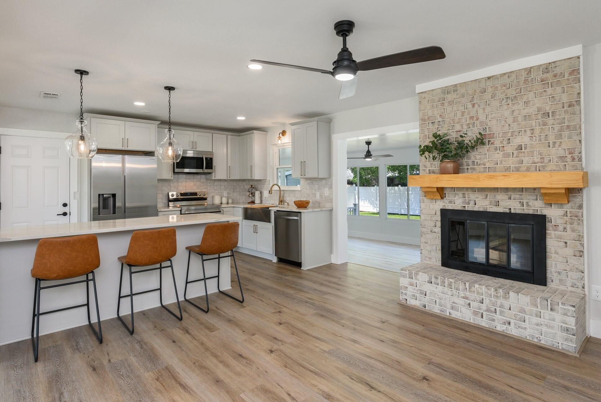 79 11th Street Shalimar, FL 32579 - Photo 2 of 36 a kitchen with stainless steel appliances granite countertop a stove top oven a refrigerator a fireplace and white cabinets with wooden floor