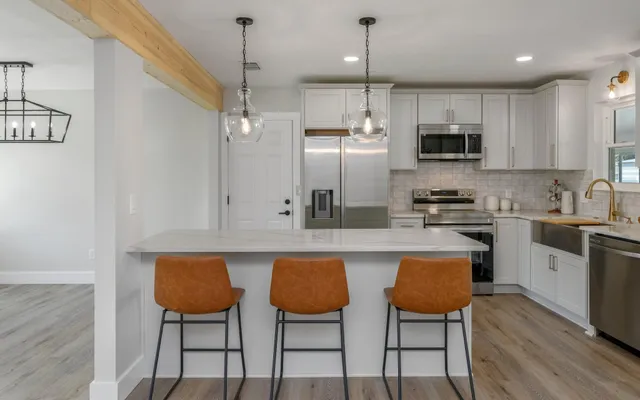 a kitchen with stainless steel appliances a table chairs refrigerator and microwave