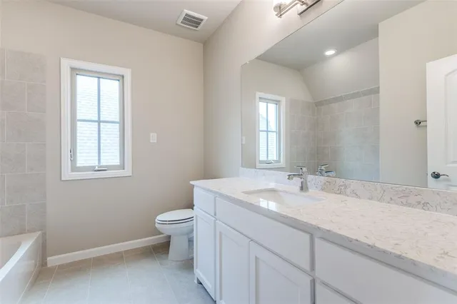 a bathroom with a granite countertop sink a toilet and a window