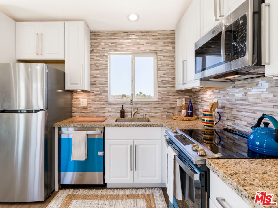 63618 2 Mile Road Joshua Tree, CA 92252 - Photo 8 of 28 a kitchen with stainless steel appliances granite countertop a stove a sink and a refrigerator