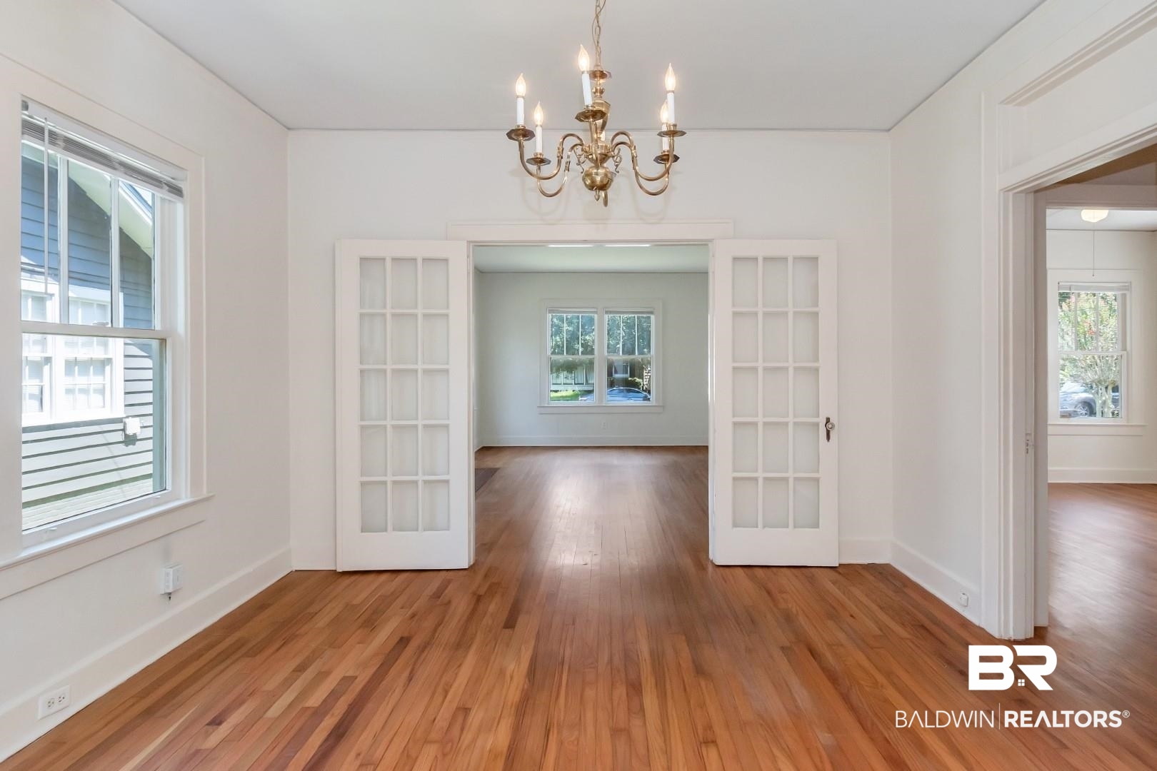 112 South Fulton Street Mobile, AL 36606 - Photo 11 of 35 Unfurnished dining area featuring hardwood / wood-style flooring, plenty of natural light, a notable chandelier, and french doors