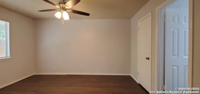 an empty room with wooden floor closet and fan