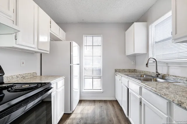 a kitchen with granite countertop a sink stove and refrigerator