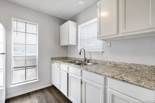a kitchen with granite countertop white cabinets and a sink