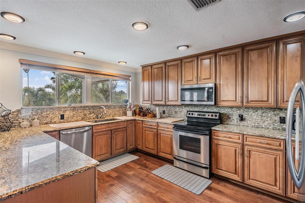 815 2nd Avenue Northwest Ruskin, FL 33570 - Photo 11 of 86 a kitchen with stainless steel appliances granite countertop a stove top oven a sink and dishwasher a refrigerator with wooden floor