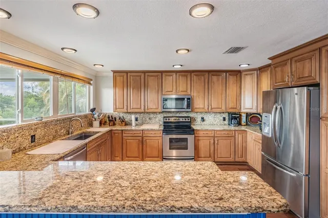 a kitchen with stainless steel appliances granite countertop wooden cabinets stove top oven and sink