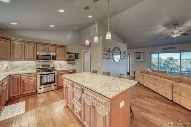 a kitchen with stainless steel appliances granite countertop a sink a stove a refrigerator cabinets and chairs