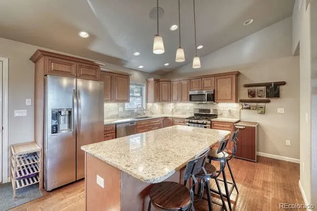 a kitchen with stainless steel appliances granite countertop a sink a stove a dining table and chairs