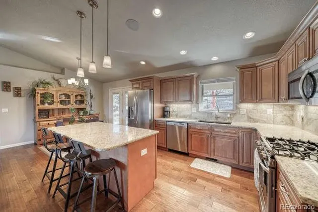a kitchen with stainless steel appliances granite countertop a stove a sink and a microwave