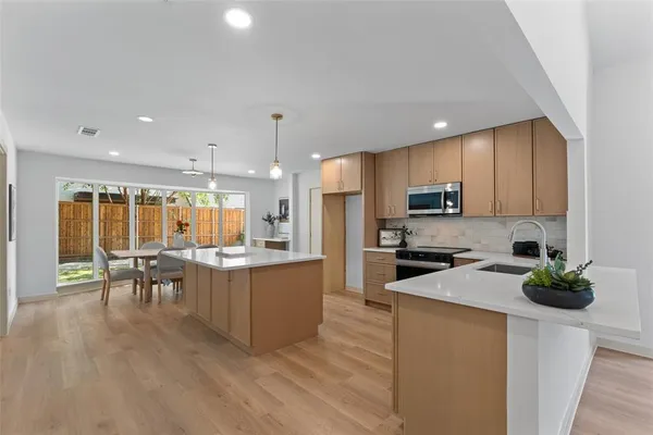 an open kitchen with wooden floor and stainless steel appliances