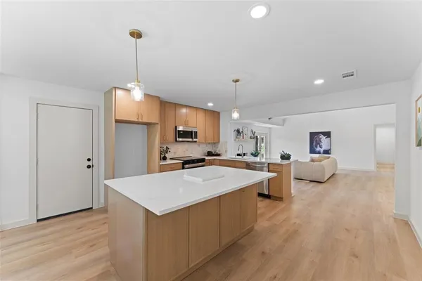 a large kitchen with kitchen island a stove a sink a center island and wooden floor