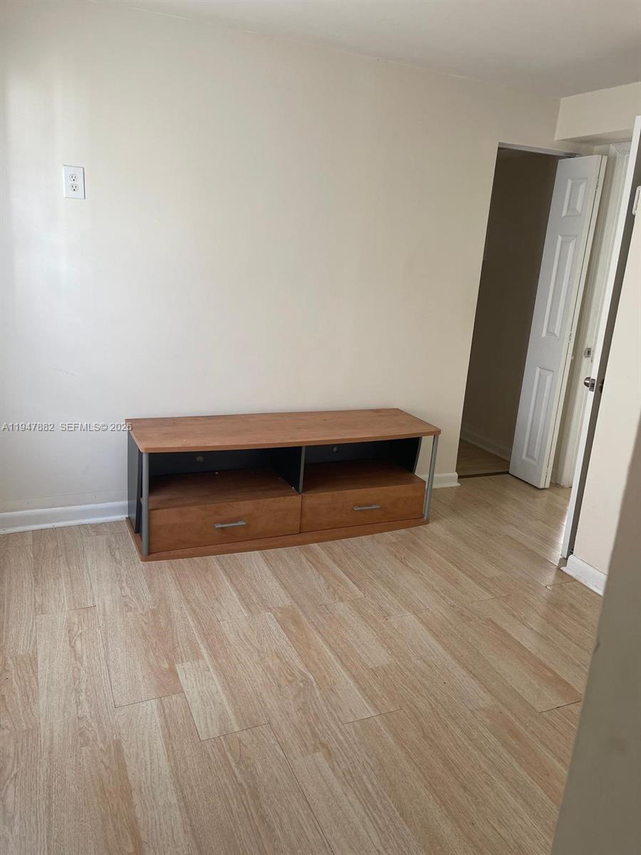 13110 Southwest 10th Street Miami, FL 33184 - Photo 9 of 12 a view of an empty room with wooden floor and a window