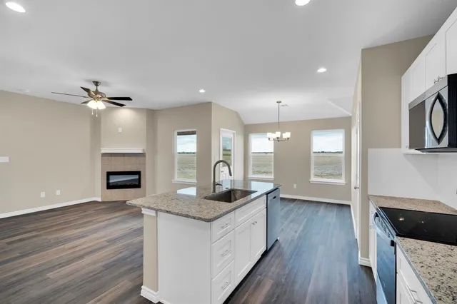 a kitchen with granite countertop kitchen island wooden floors granite counter tops and a fireplace