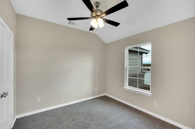 an empty room with windows and fan