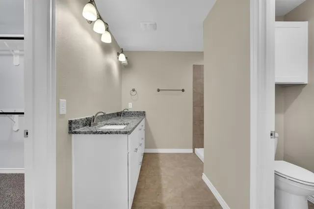 a bathroom with a granite countertop sink a toilet and a mirror