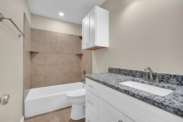 a bathroom with a granite countertop sink a toilet and bathtub