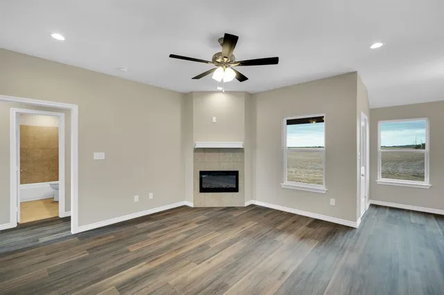 a view of an empty room with wooden floor fireplace and a window