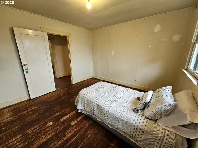 a bedroom with a bed and wooden floor