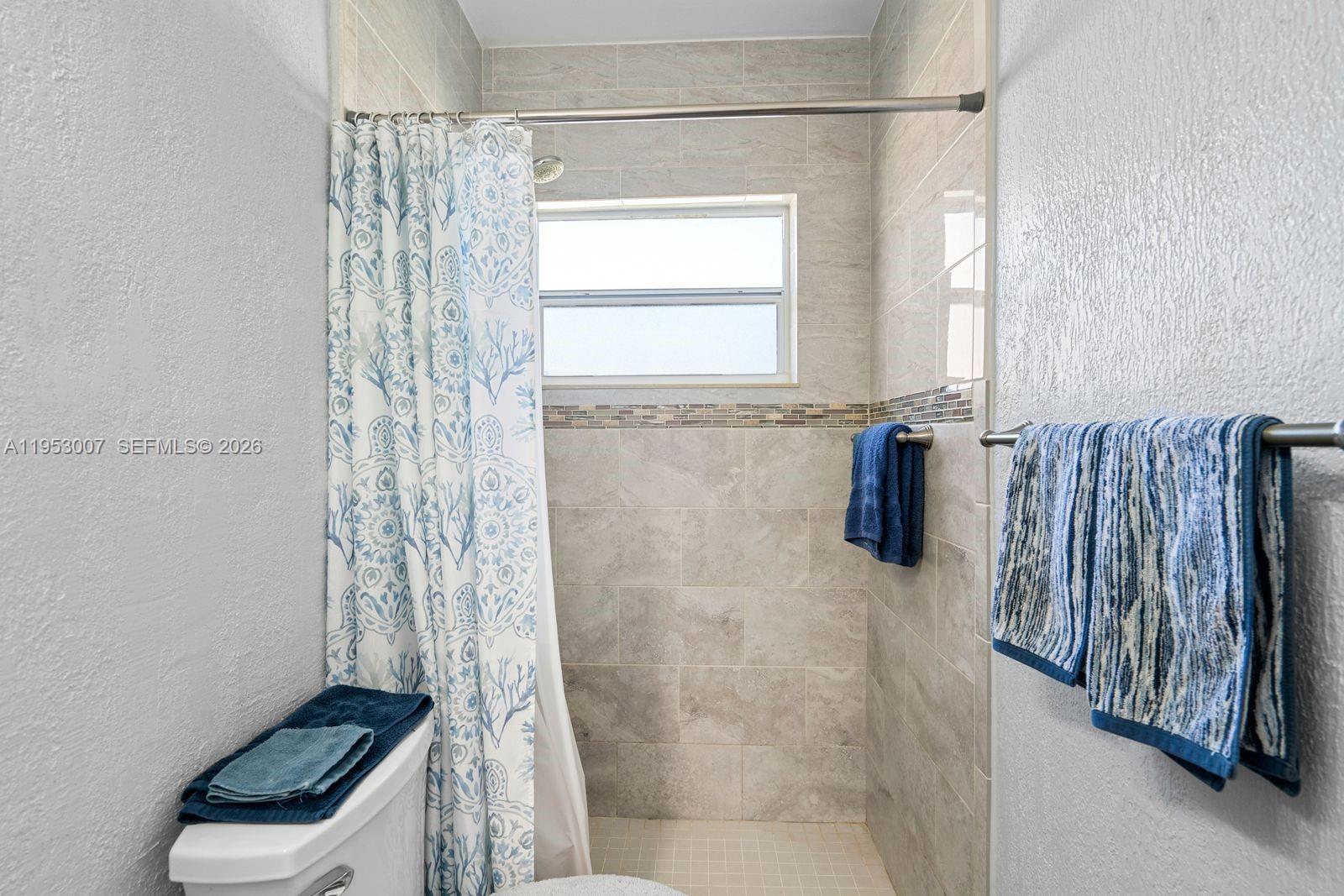 5770 Northwest 111th Street Hialeah, FL 33012 - Photo 26 of 32 a bathroom with a shower curtain and a window