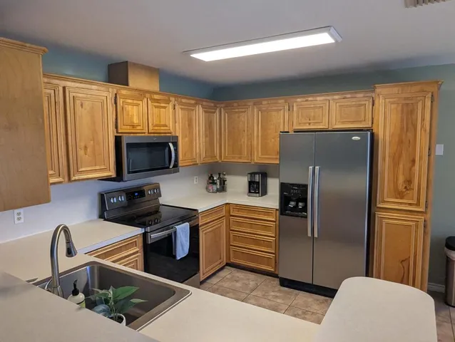 a kitchen with granite countertop a stove a sink dishwasher a dining table and chairs with wooden floor