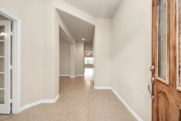 an empty room with windows and chandelier fan